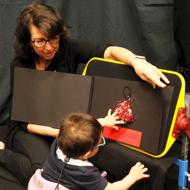 Teacher placing bright red objects on black board with child facing away from camera looking at the board