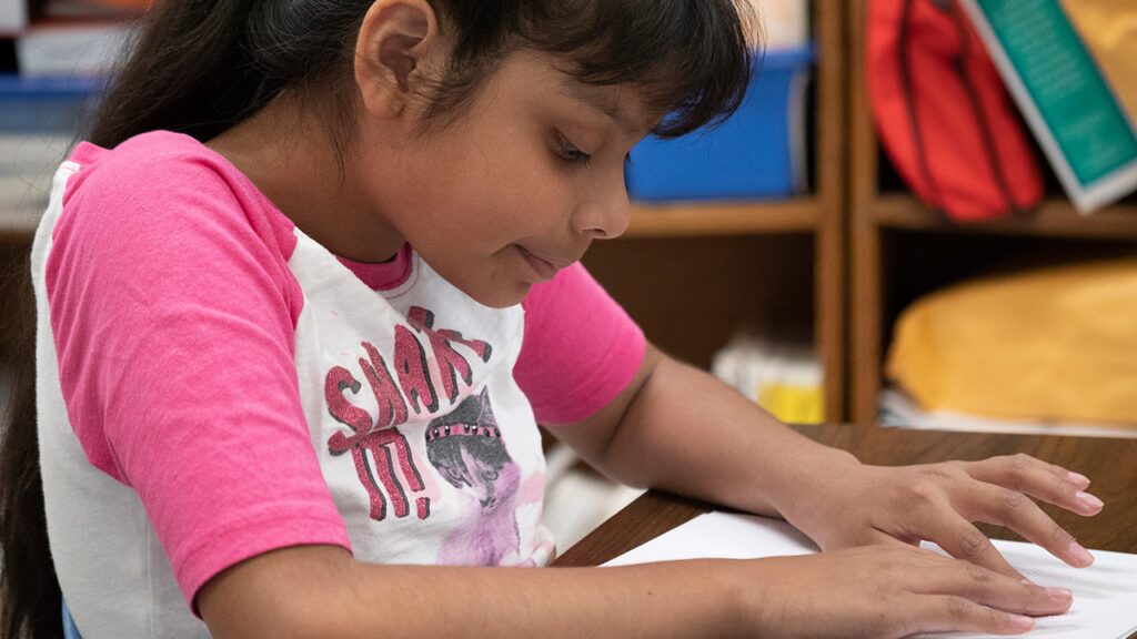 young girl reading braille with both hands