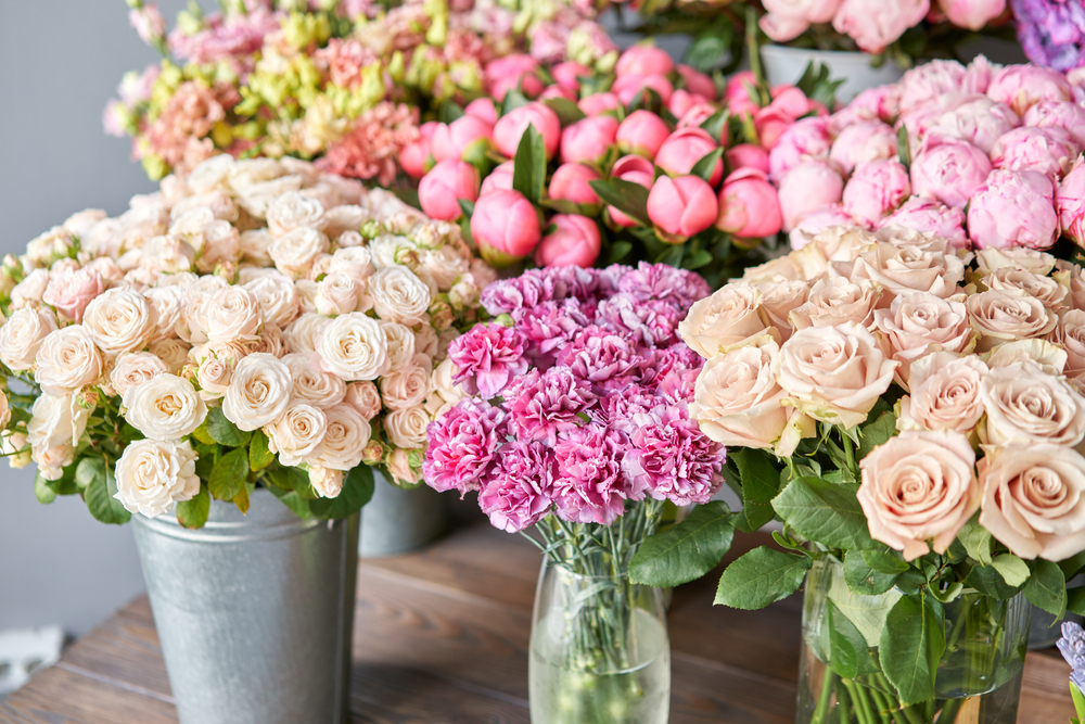 Many different color flowers on the stand or wooden table in the flower shop.