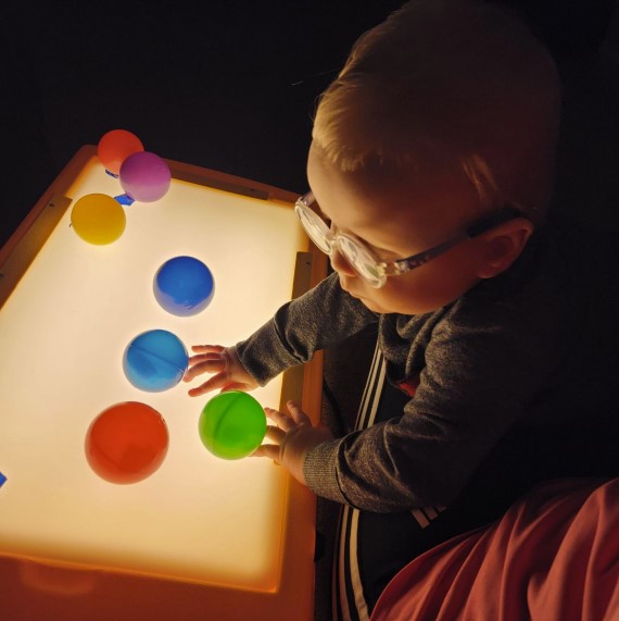 Dominic is playing with an AMP light box. He has colorful balls stuck on it.