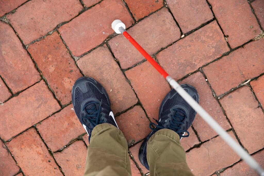 Individual using a white cane with a marshmallow cane tip