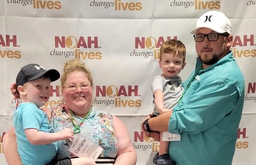 Family of four in front of a NOAH backdrop