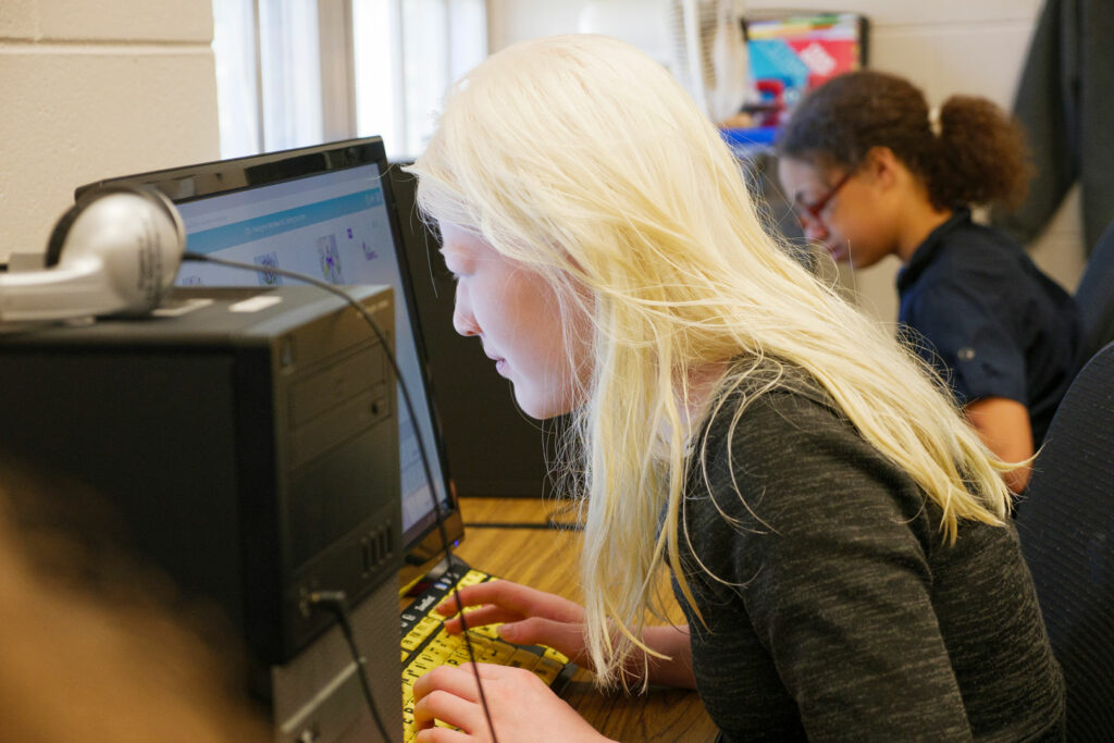 A blond student leaning into a computer with text enlarged. 