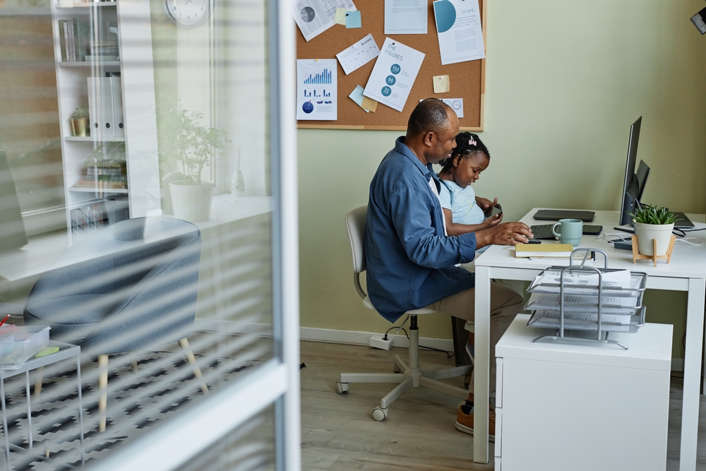 Preschool age child sitting on father’s lap in an office setting