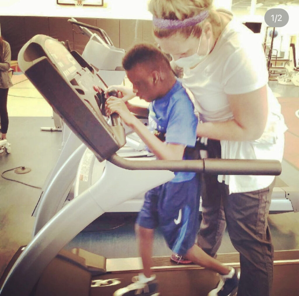 Child walking on a treadmill with an adult's support